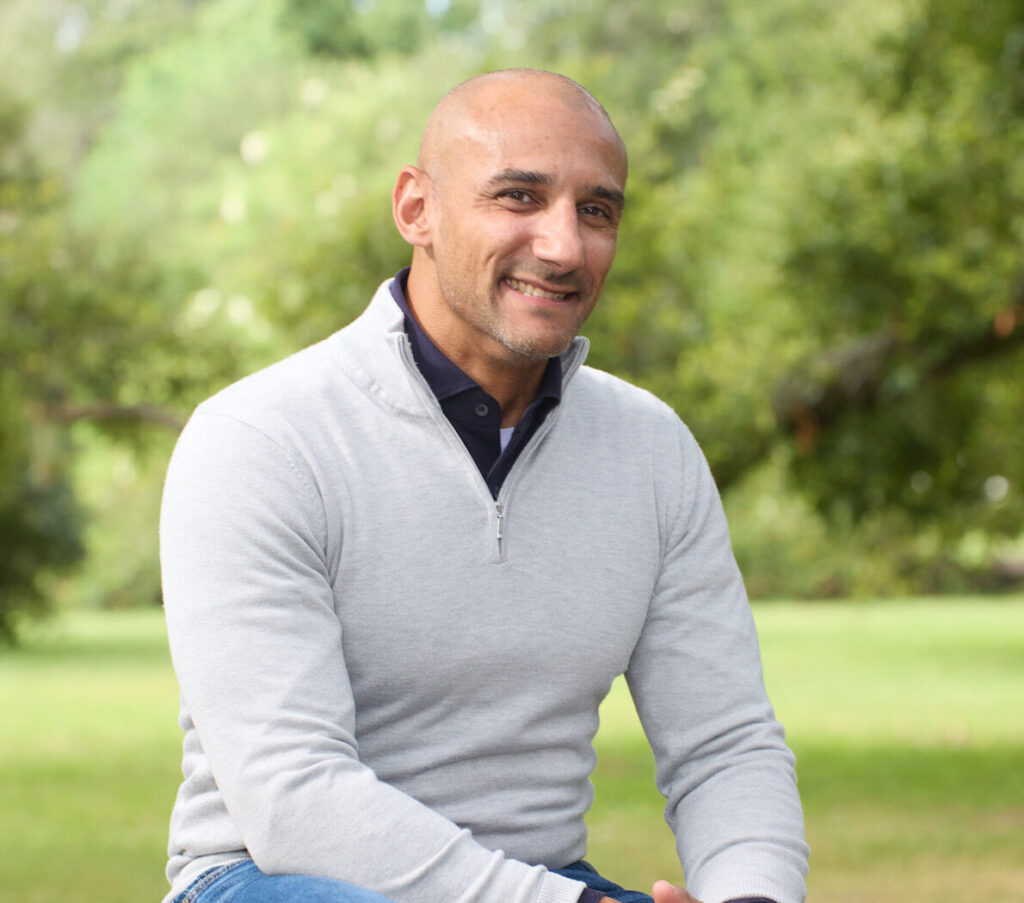 Image of founder and CEO of FiveM sitting on a bench with trees behind