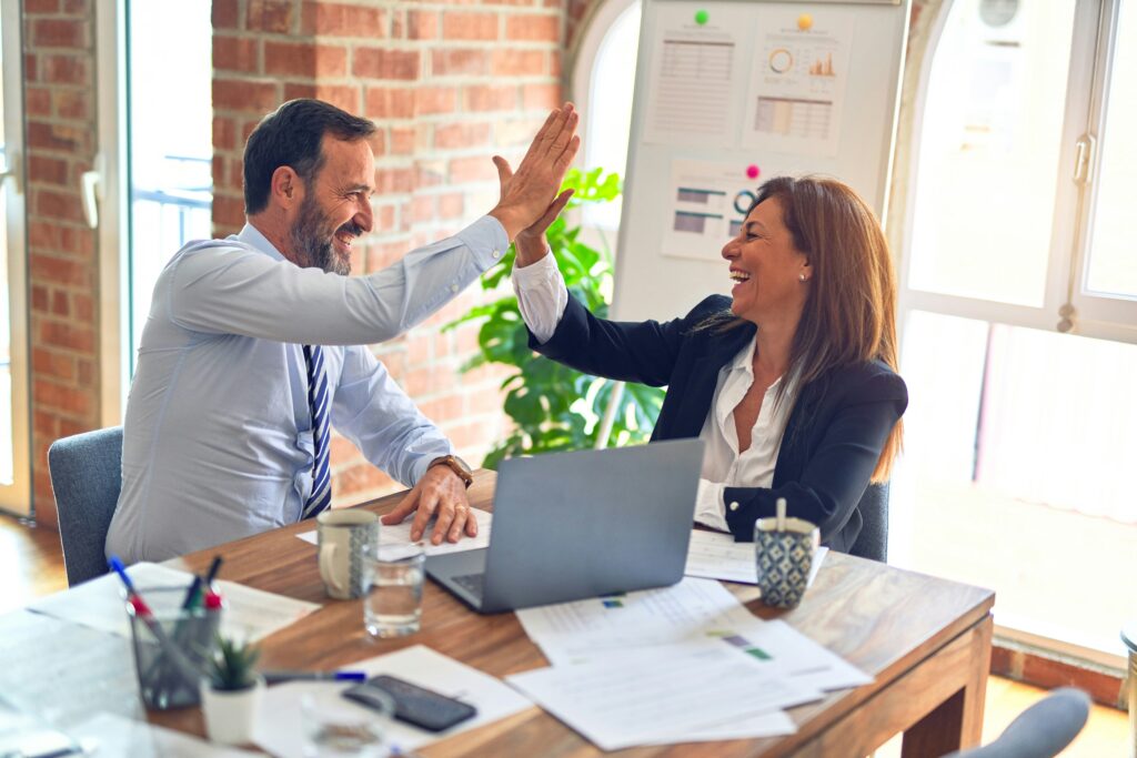 two professionals in a meeting highfiving